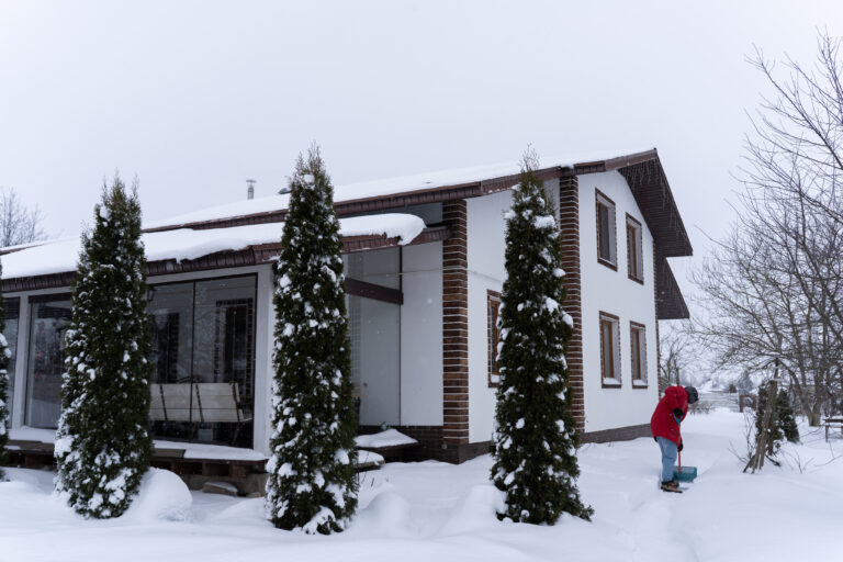 Casa cubierta de nieve con árboles de hoja perenne en invierno