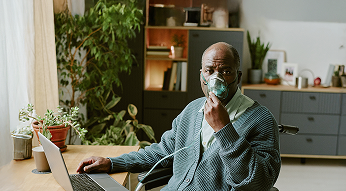 Man using oxygen mask while working on laptop at home
