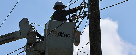 Electric utility worker on power line at dusk
